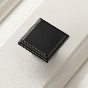 Primer plano del pomo o botón de mueble de diseño minimalista cuadrado color negro mate (Botón Cuadrado Negro).