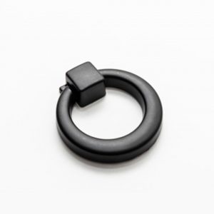 Tirador de mueble tipo argolla o aro modelo Lima en acabado negro mate sobre cajón de madera oscura.