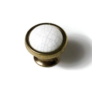 Pomo o botón de mueble en porcelana blanca con efecto craquelado y base de metal dorado envejecido.